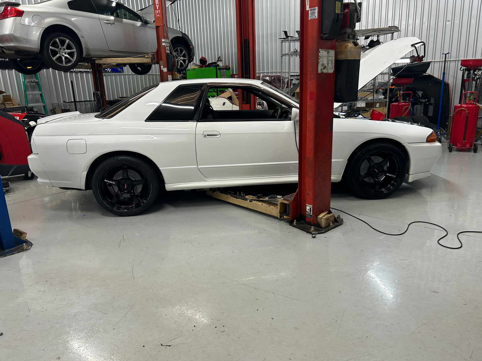 White R32 Skyline beside a workshop vehicle lift