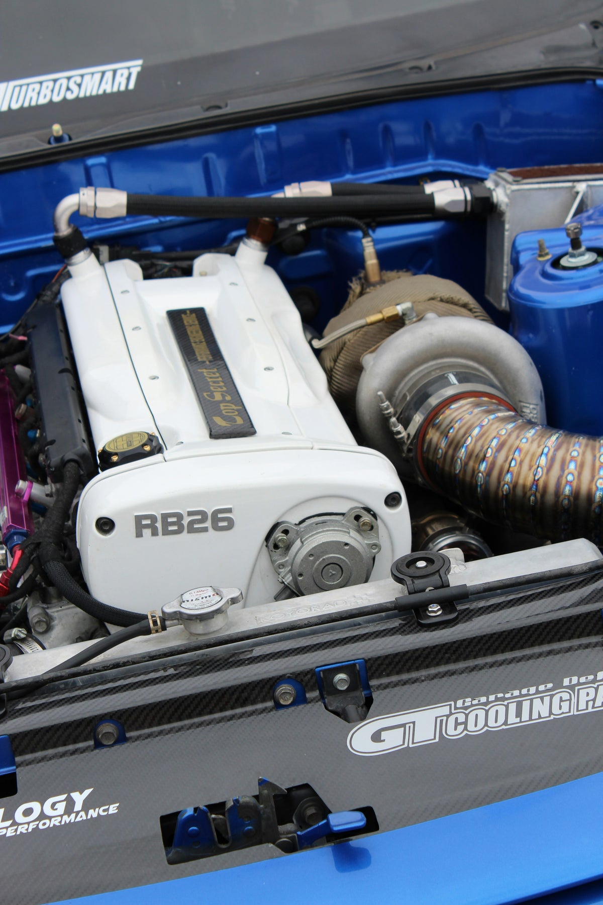 R33 engine bay with a white RB26 engine cover, turbocharger and metal intake piping