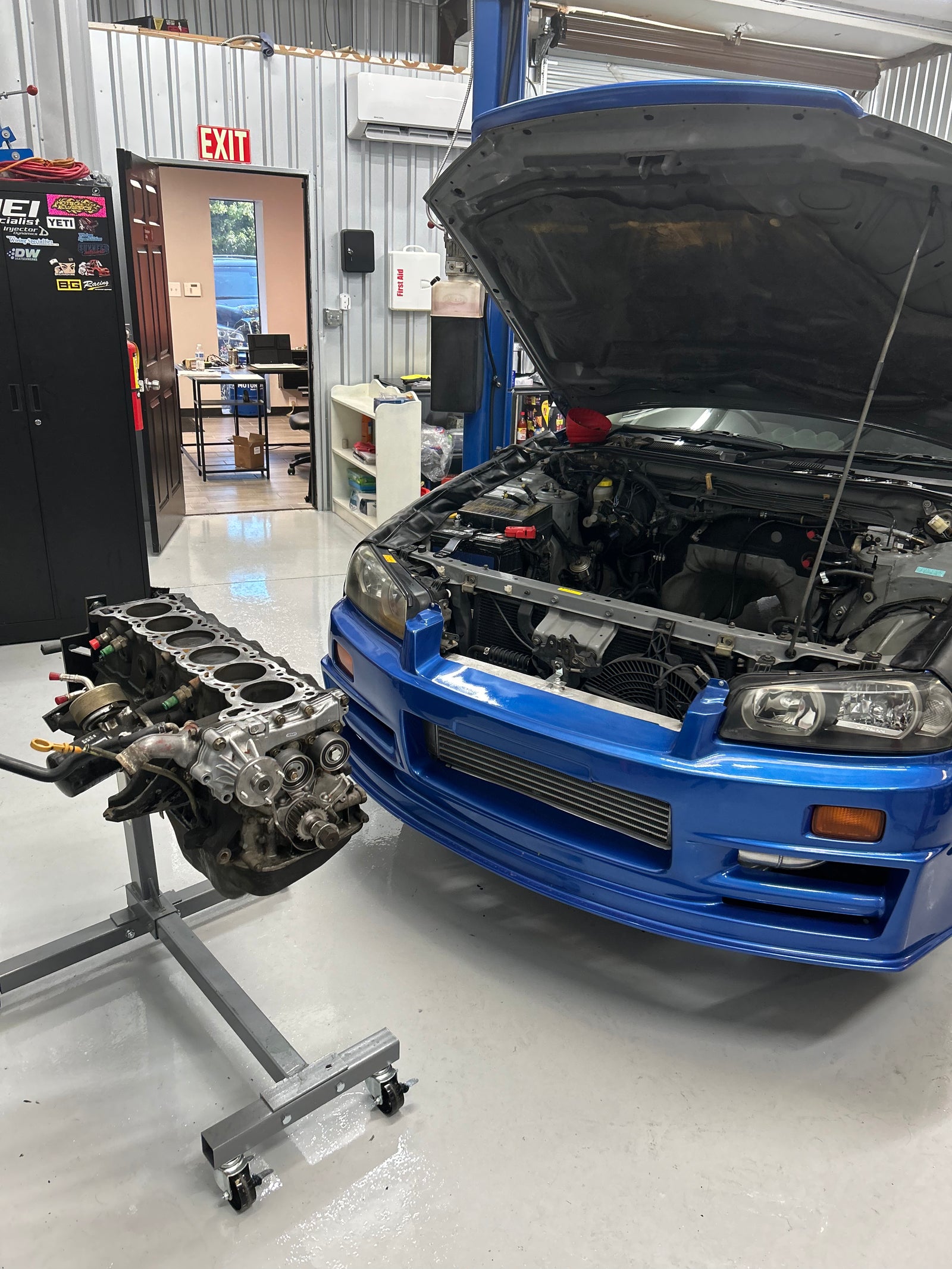 Blue R34 Skyline with an engine in the workshop