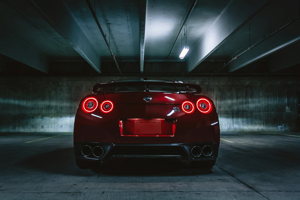 Rear view of a red Nissan GT-R with illuminated taillights in a parking garage