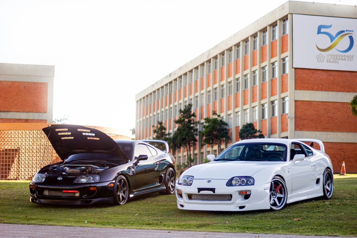 White and black MK4 Toyota Supras parked together