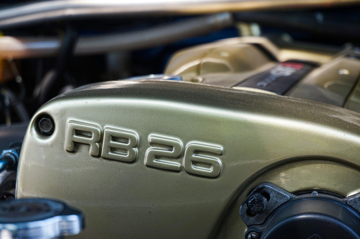 Close-up of a metallic RB26 engine cover in an engine bay
